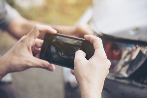 Someone taking a photo of car crash damage.