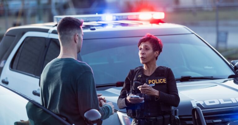 tall, young male driver giving statement after a crash to black female police officer