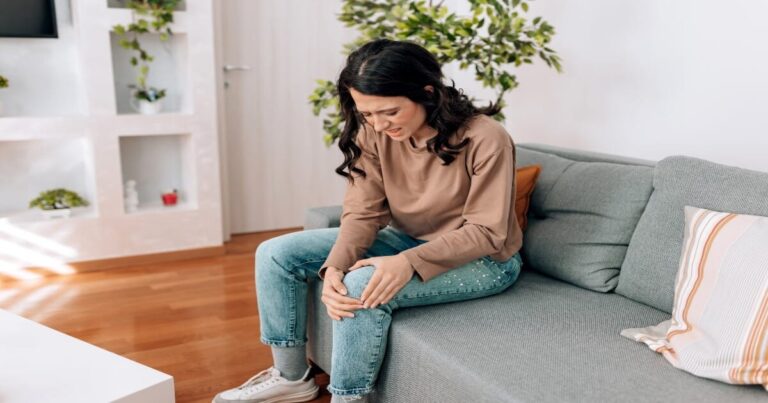 A woman holding her knee in pain.