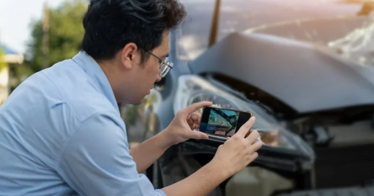 A man that is taking a picture of his car damage.