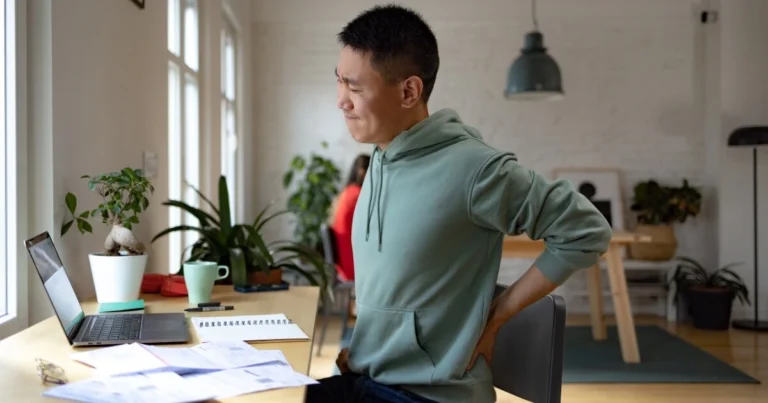 A person having back pain at their desk.