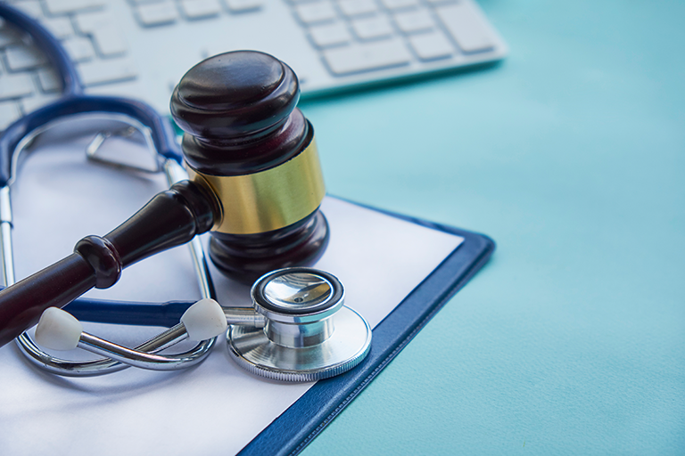 Gavel and stethoscope on clipboard, symbolizing medical law and healthcare legislation against a keyboard backdrop.